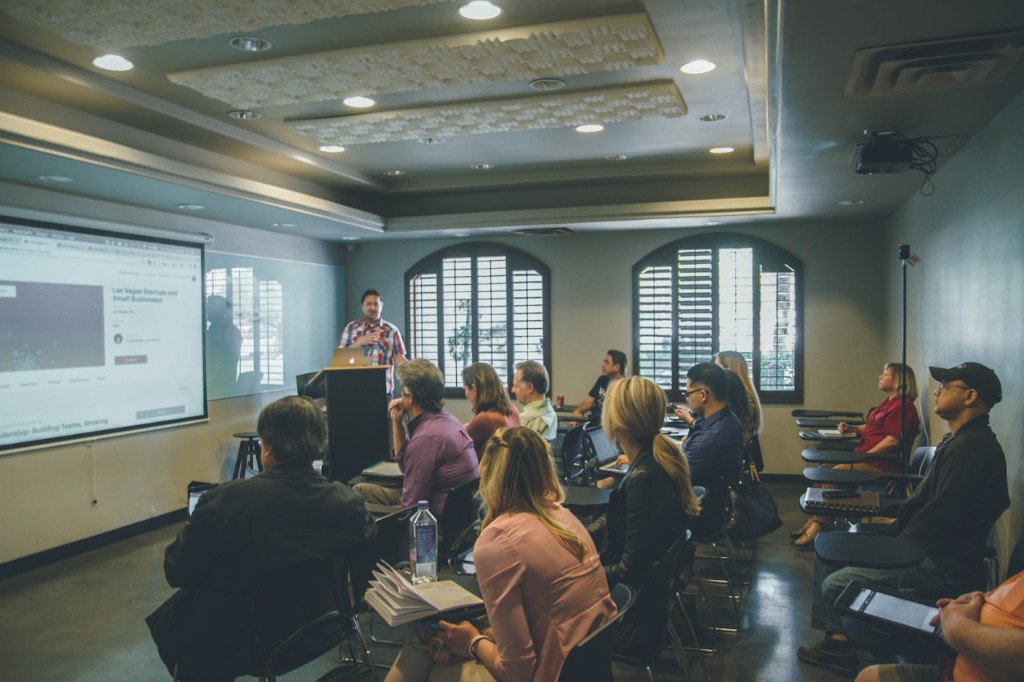 A presenter speaking to seated participants in a classroom